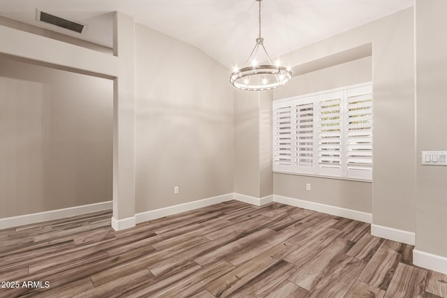 unfurnished dining area with visible vents, lofted ceiling, wood finished floors, baseboards, and a chandelier