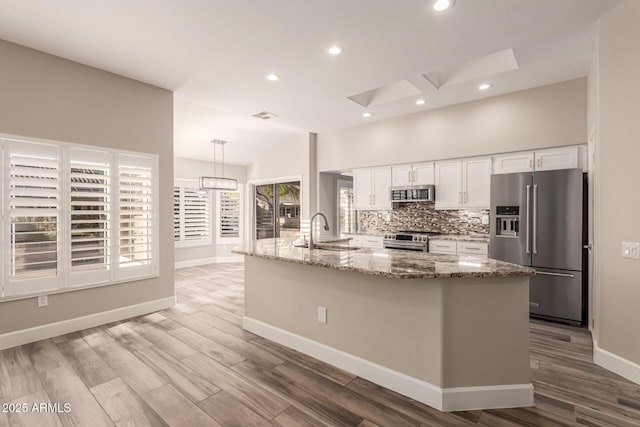 kitchen featuring a sink, white cabinets, light wood finished floors, and high quality appliances