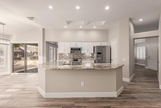 kitchen featuring visible vents, light stone countertops, white cabinetry, a sink, and stainless steel appliances