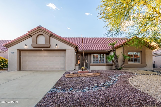 mediterranean / spanish home with a garage, stucco siding, concrete driveway, and a tiled roof