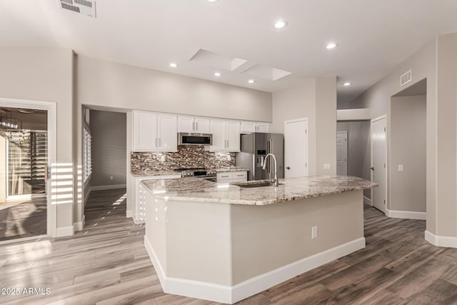 kitchen with white cabinets, stainless steel appliances, visible vents, and light wood finished floors