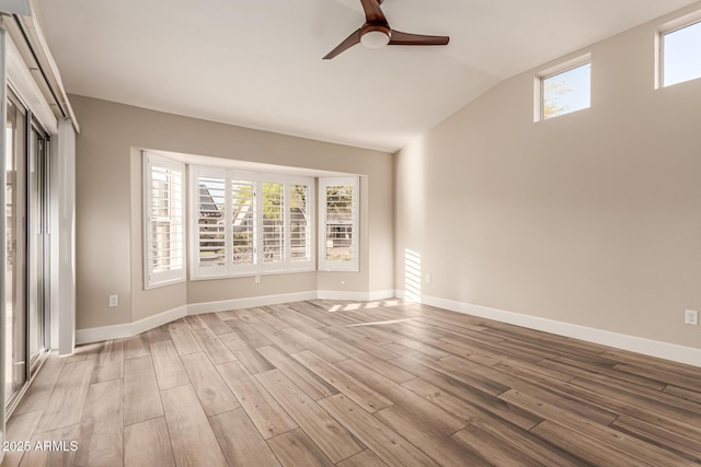 empty room featuring wood finished floors, baseboards, ceiling fan, and lofted ceiling