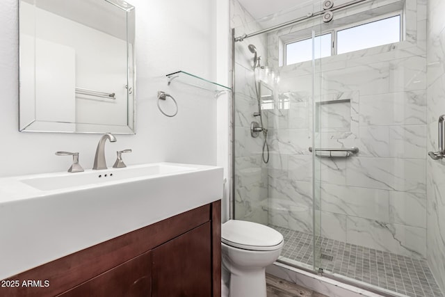 full bathroom featuring vanity, a marble finish shower, and toilet