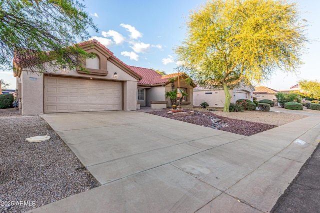 mediterranean / spanish-style home with a tiled roof, an attached garage, driveway, and stucco siding