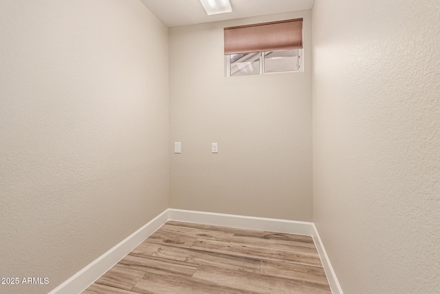 laundry room with baseboards and light wood-style flooring