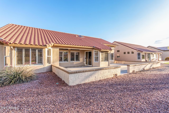 rear view of house with a tile roof, a patio area, and stucco siding