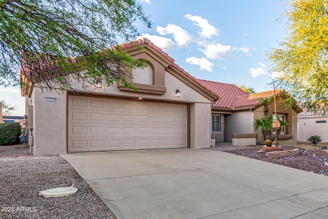mediterranean / spanish home with a garage, stucco siding, a tiled roof, and driveway