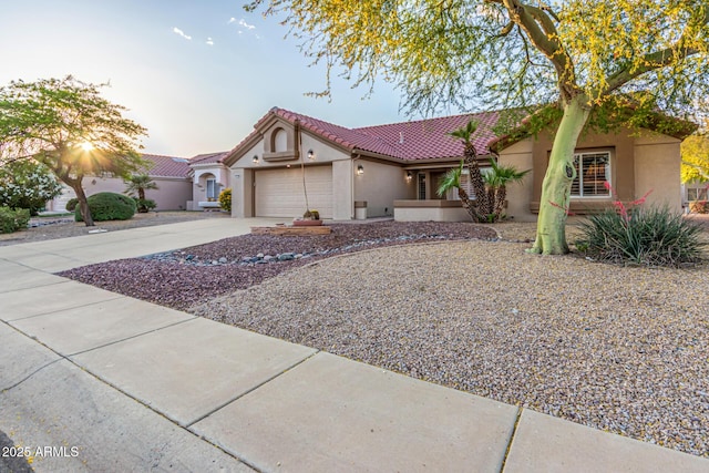 view of front facade with an attached garage, stucco siding, driveway, and a tiled roof