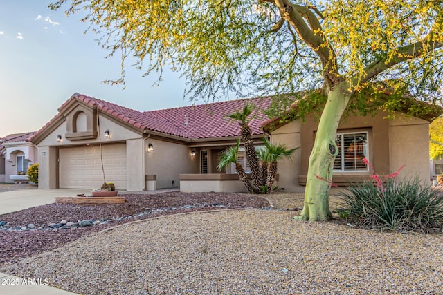 mediterranean / spanish-style house featuring concrete driveway, an attached garage, a tile roof, and stucco siding