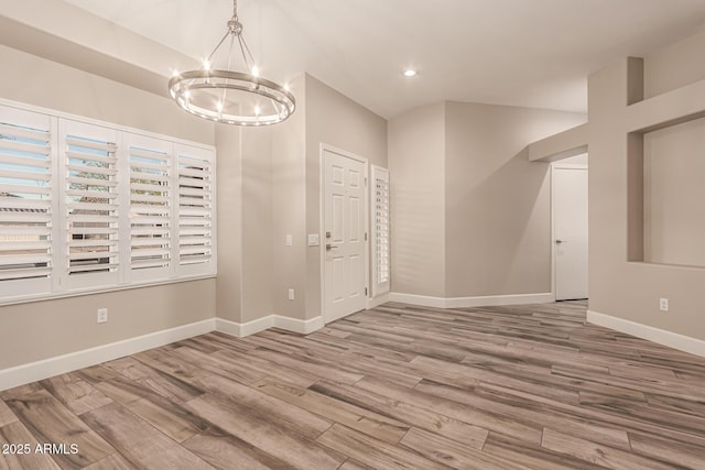 spare room with recessed lighting, baseboards, a notable chandelier, and wood finished floors