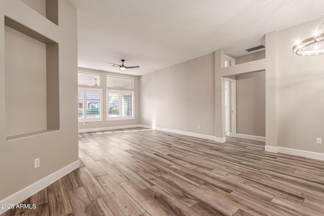 empty room featuring baseboards, ceiling fan, visible vents, and wood finished floors