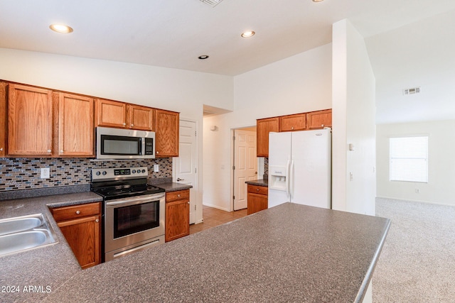 kitchen featuring backsplash, appliances with stainless steel finishes, high vaulted ceiling, sink, and light colored carpet