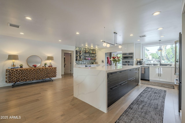 kitchen with visible vents, stainless steel appliances, a large island, white cabinets, and modern cabinets