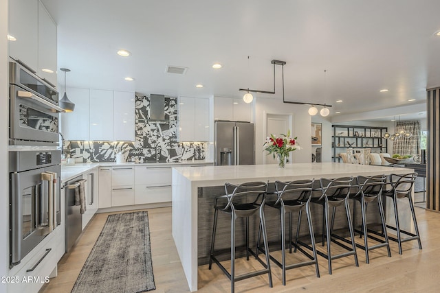 kitchen featuring stainless steel appliances, modern cabinets, a center island, and white cabinetry