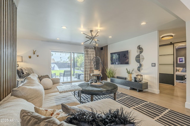 living room featuring a barn door, a notable chandelier, recessed lighting, and light wood finished floors