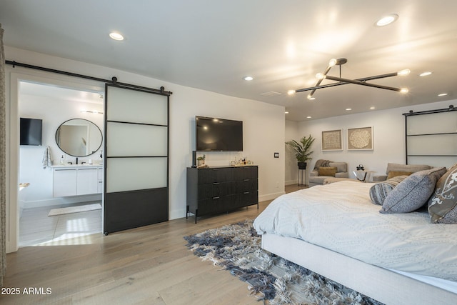 bedroom featuring light wood-type flooring, a notable chandelier, recessed lighting, a barn door, and baseboards