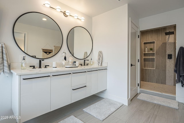 bathroom featuring a sink, baseboards, tiled shower, and double vanity