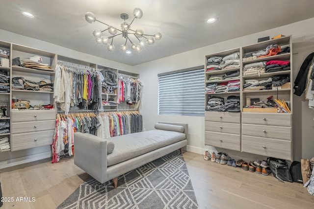 walk in closet with an inviting chandelier and wood finished floors