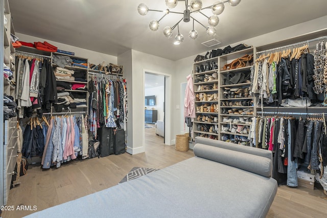 spacious closet featuring a notable chandelier, visible vents, and wood finished floors