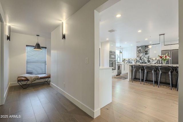 hall featuring visible vents, recessed lighting, light wood-type flooring, and baseboards