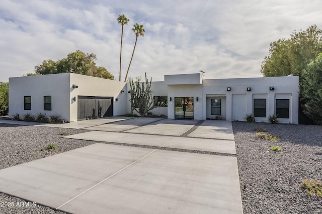 contemporary house with concrete driveway, a garage, and stucco siding