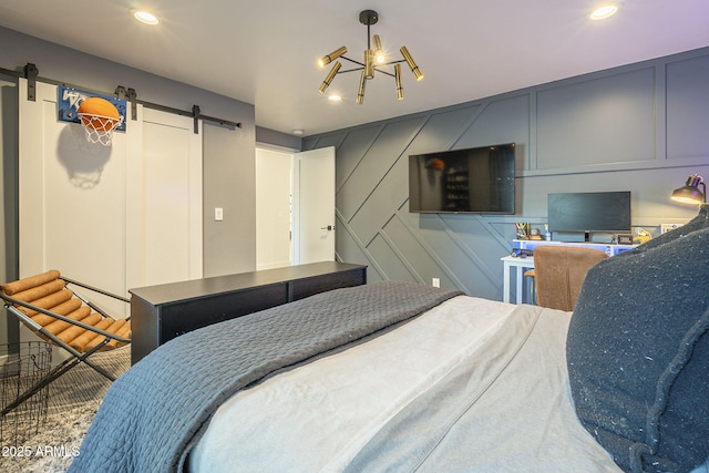 bedroom featuring a barn door, a decorative wall, and recessed lighting