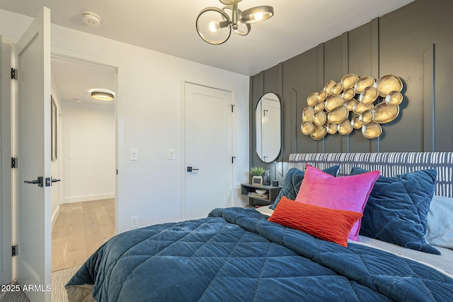 bedroom with baseboards, a notable chandelier, and wood finished floors