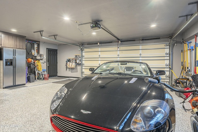 garage featuring a garage door opener and stainless steel refrigerator with ice dispenser