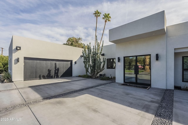 view of front of property with stucco siding, driveway, and a garage