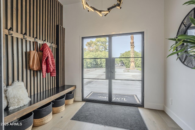 mudroom featuring a notable chandelier, wood finished floors, baseboards, and french doors