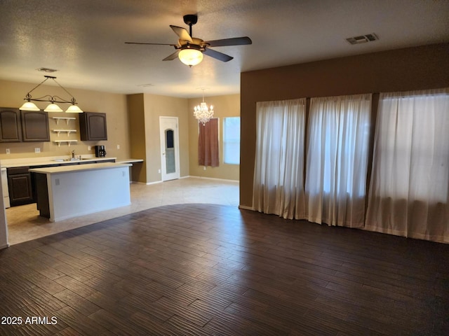 kitchen with ceiling fan with notable chandelier, a center island, light hardwood / wood-style floors, and decorative light fixtures