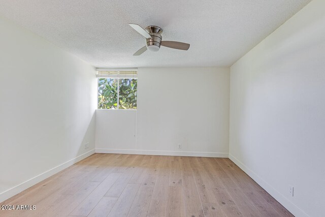 spare room with light wood-type flooring, a textured ceiling, and ceiling fan