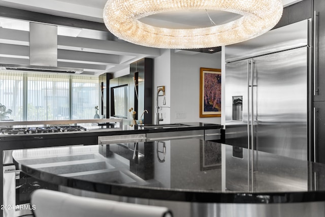 kitchen with dark stone countertops, sink, stainless steel appliances, and wall chimney range hood