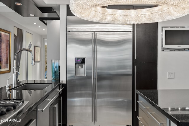 kitchen featuring sink, stainless steel built in refrigerator, and dark stone counters