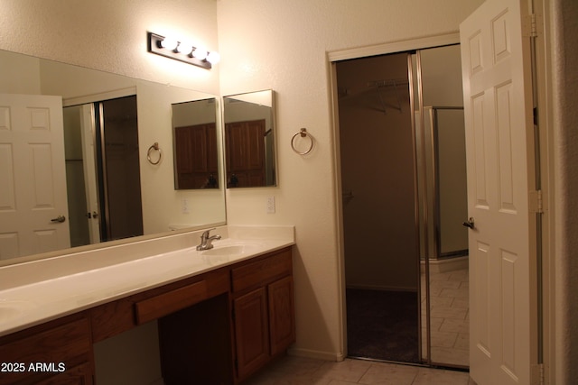 14543 W Bison Path, Surprise, AZ 85374 - full bathroom featuring double vanity, tile patterned flooring, a walk in closet, and an enclosed shower