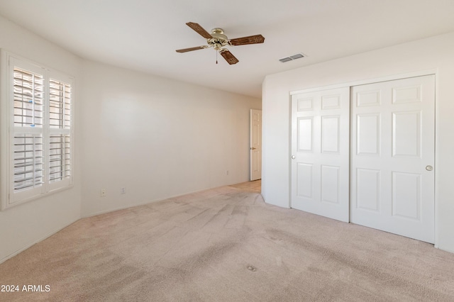 unfurnished bedroom featuring ceiling fan, light colored carpet, and a closet