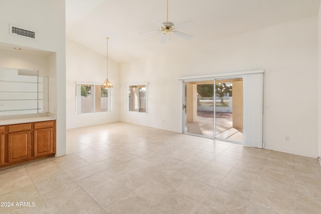 tiled empty room with ceiling fan with notable chandelier and high vaulted ceiling