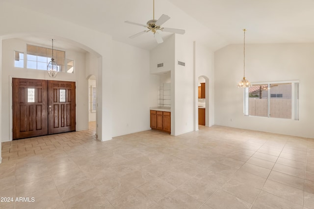 tiled foyer entrance featuring ceiling fan with notable chandelier and high vaulted ceiling