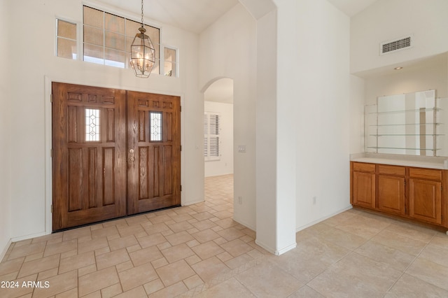 tiled foyer featuring a chandelier and a towering ceiling