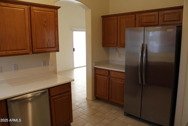 14543 W Bison Path, Surprise, AZ 85374 - kitchen with stainless steel appliances, arched walkways, brown cabinetry, and light countertops