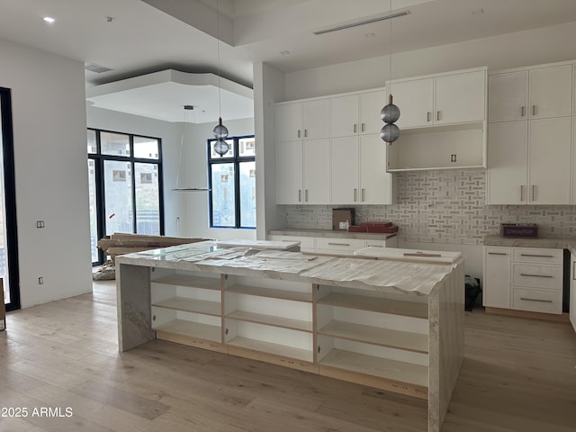 kitchen featuring open shelves, decorative backsplash, a kitchen island, and light wood-style flooring