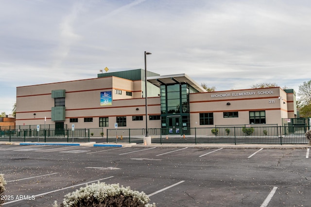 view of building exterior with uncovered parking and fence