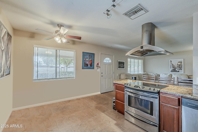 kitchen featuring brown cabinets, island exhaust hood, stainless steel appliances, visible vents, and baseboards