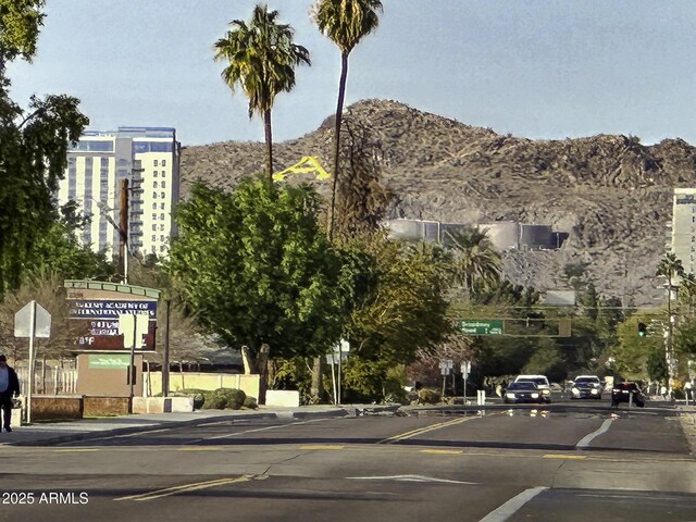 view of street featuring traffic signs, curbs, a mountain view, and sidewalks