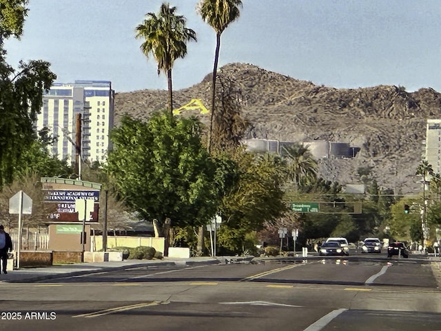 view of street featuring curbs, traffic signs, sidewalks, and a mountain view