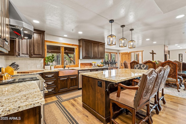 7500 E Old Walnut Canyon Rd, Flagstaff, AZ 86004 - kitchen with light wood finished floors, a breakfast bar, wall chimney exhaust hood, a kitchen island, and a sink