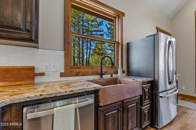 7500 E Old Walnut Canyon Rd, Flagstaff, AZ 86004 - kitchen featuring decorative backsplash, light wood finished floors, stainless steel appliances, dark brown cabinets, and a sink