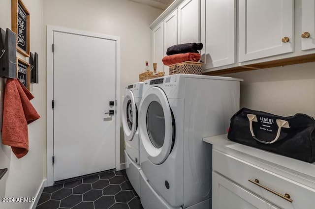 laundry room featuring washer and clothes dryer, dark tile patterned flooring, and cabinets