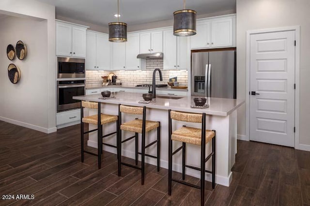 kitchen featuring an island with sink, dark hardwood / wood-style floors, a breakfast bar, and appliances with stainless steel finishes