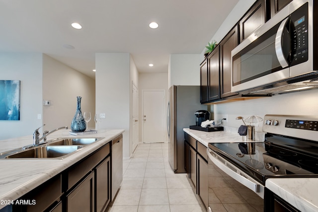 kitchen featuring appliances with stainless steel finishes, sink, light tile patterned floors, dark brown cabinetry, and light stone countertops